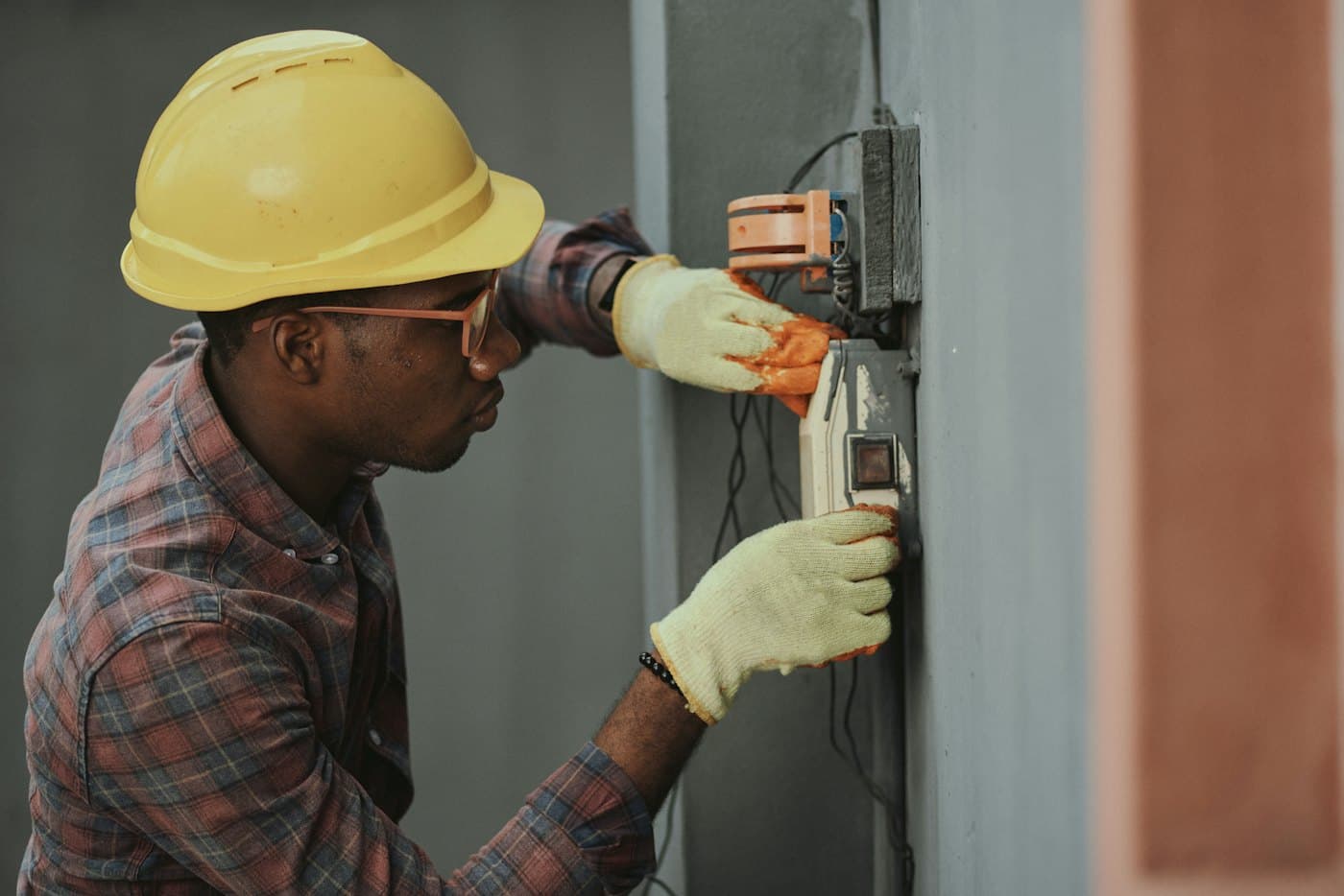 Technician in a hard hat testing an electrical meter