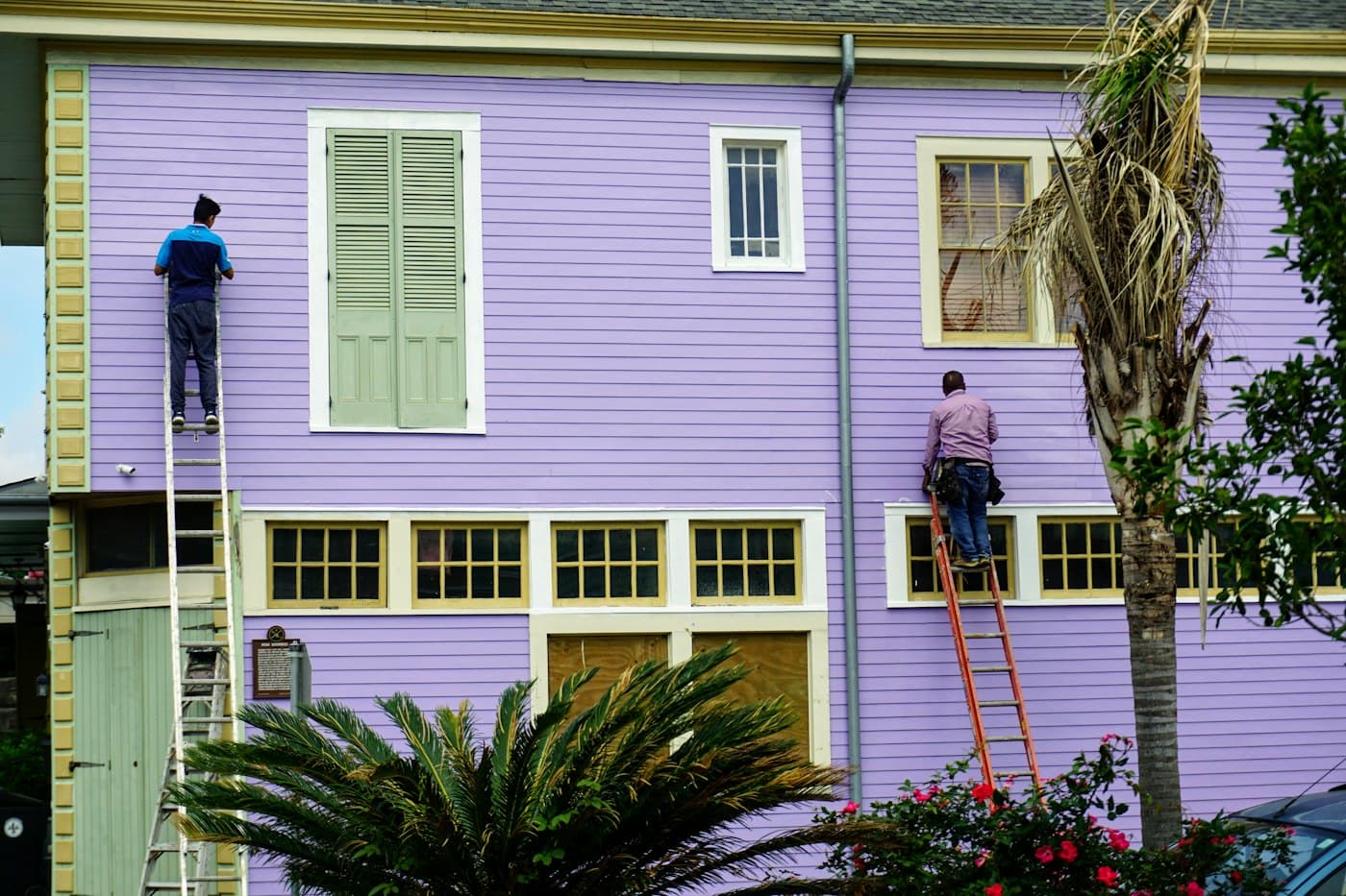 Painters on ladders repainting a house exterior