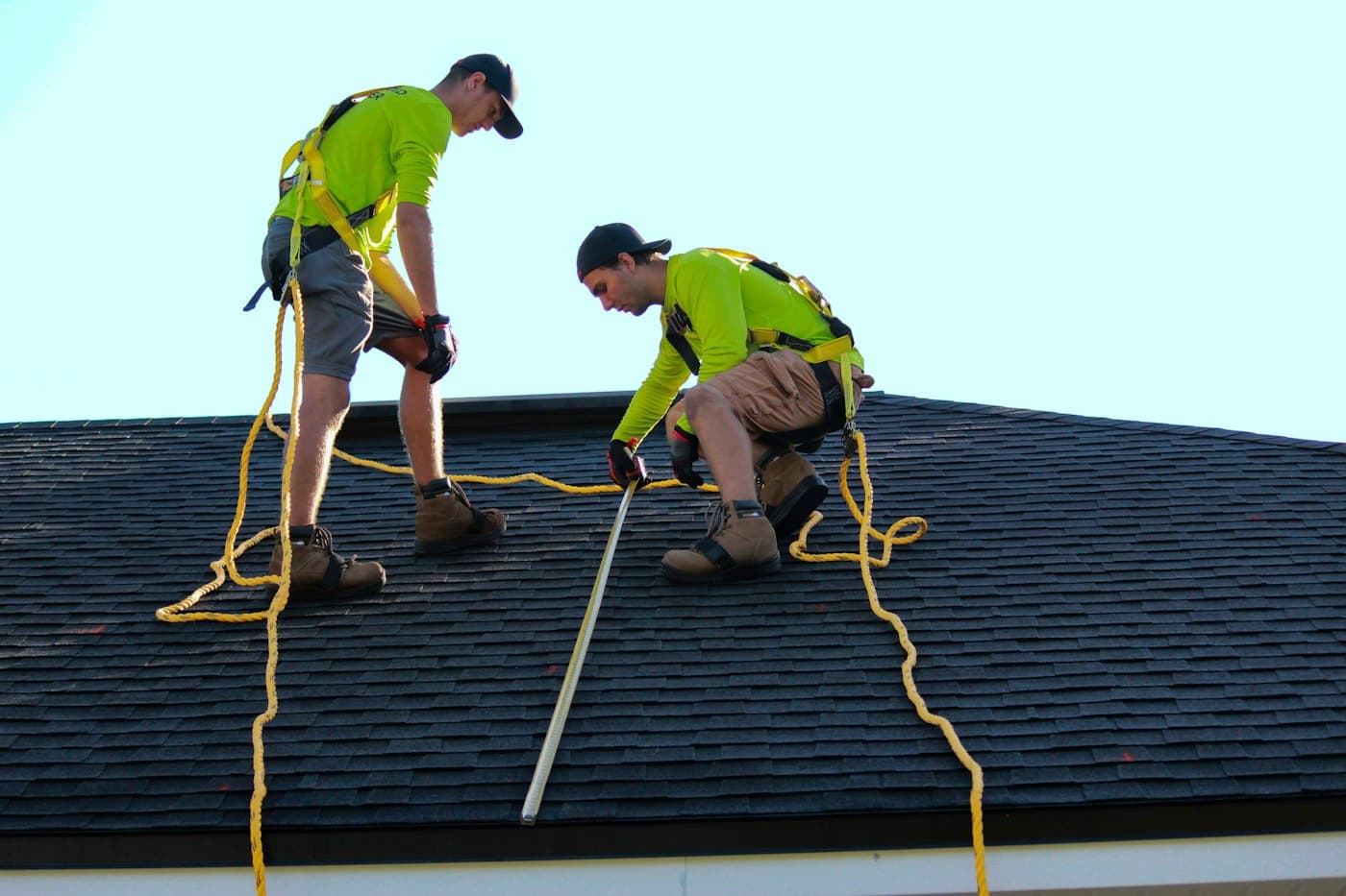 Two workers inspecting a roof with safety lines